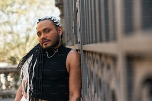 a man with dreadlocks leaning against a wall