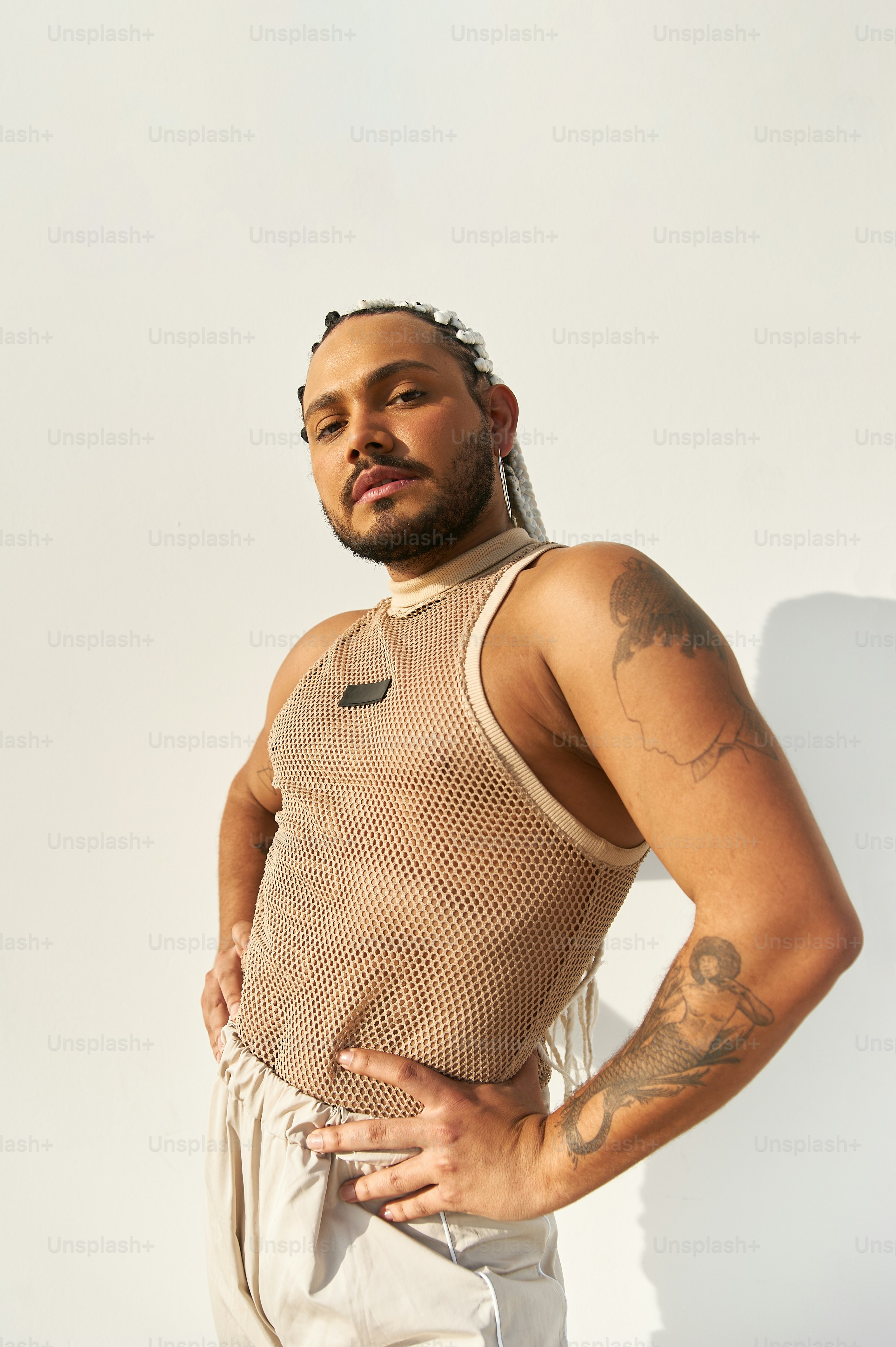 a man with tattoos standing with his hands on his hips