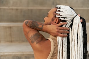 a man with dreadlocks on his head is sitting on the steps