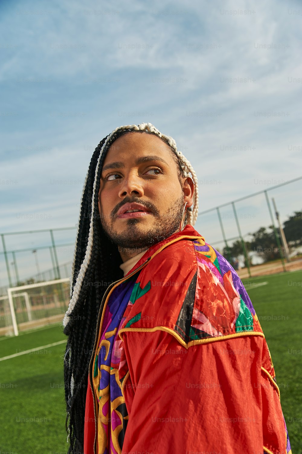 a man with dreadlocks standing on a soccer field