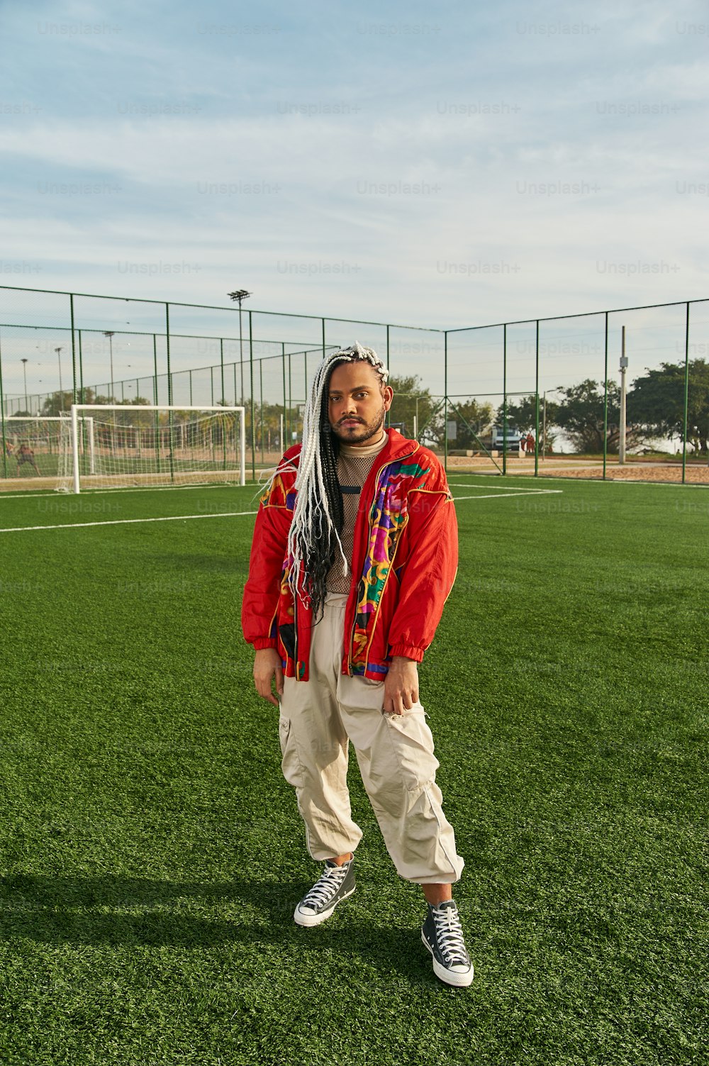 um homem com cabelos compridos em pé em um campo de futebol