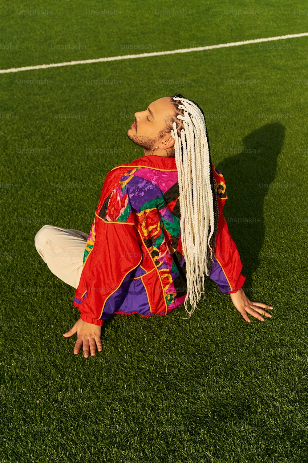 a man with long white hair sitting on a soccer field