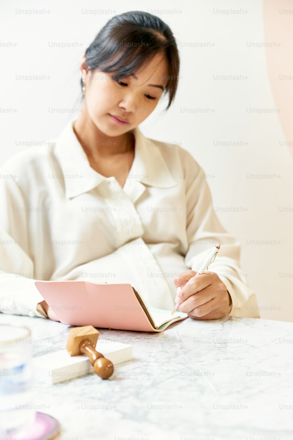 a woman sitting at a table writing in a notebook