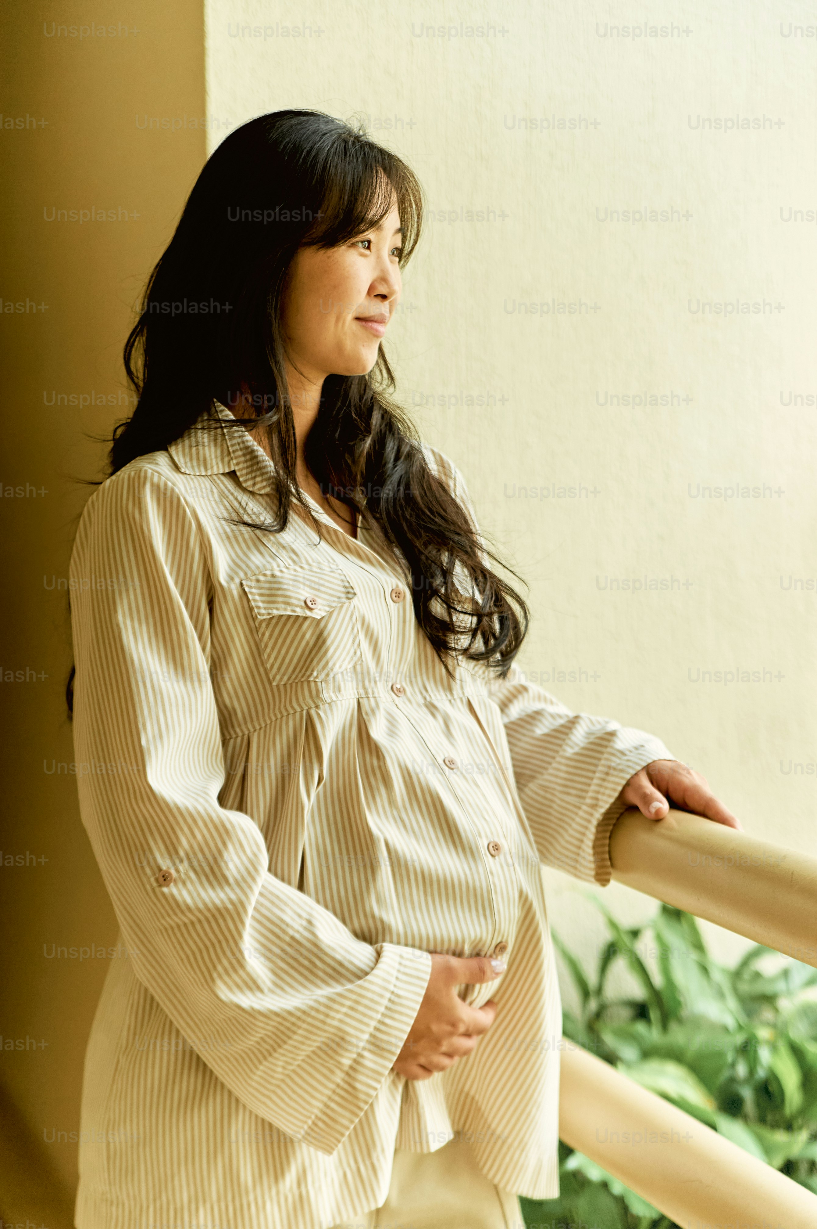 a pregnant woman standing on a balcony next to a railing
