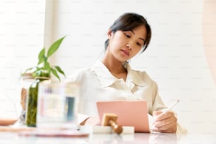 a woman sitting at a table writing on a piece of paper