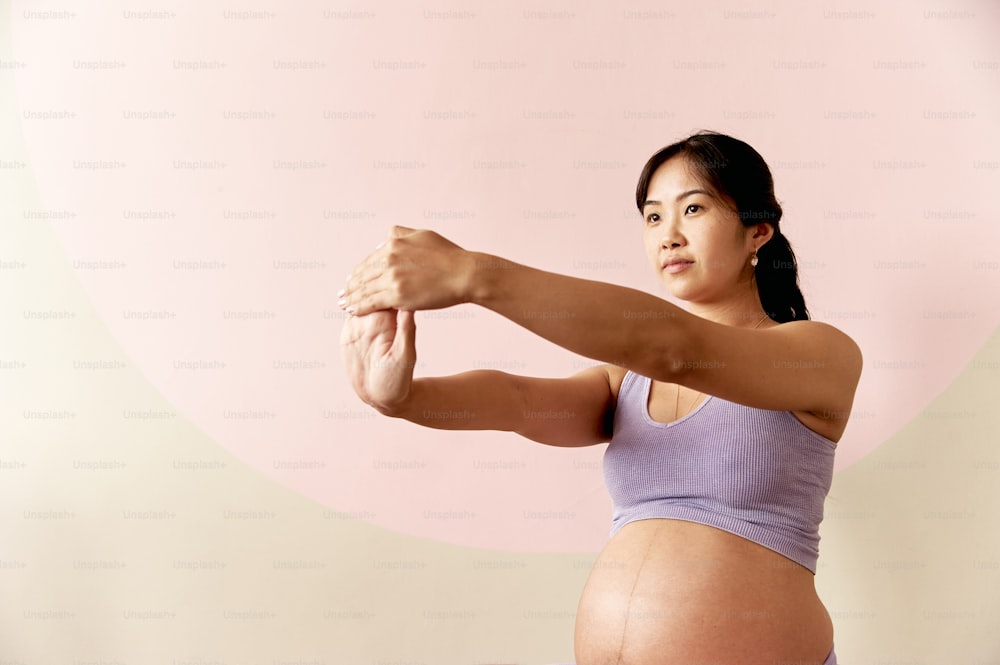 Una mujer embarazada flexionando sus músculos para una foto