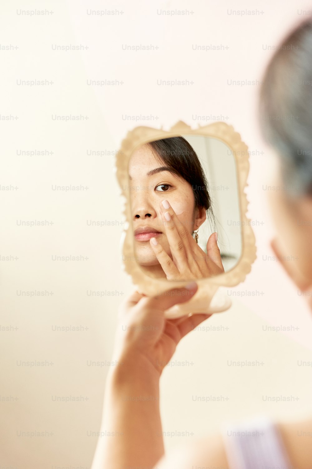 a woman looking at her face in the mirror