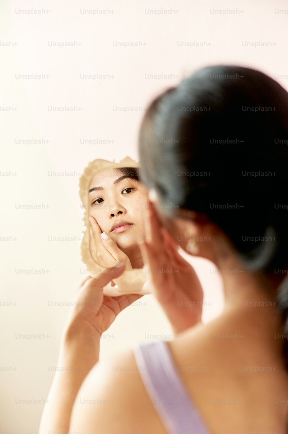 uma mulher olhando para seu rosto no espelho