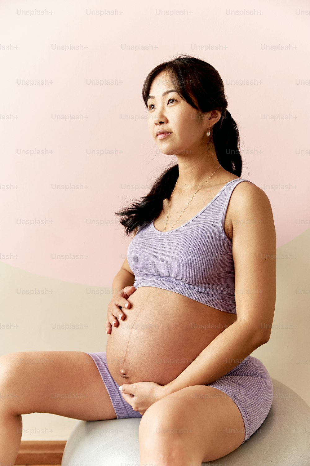 a pregnant woman sitting on top of a ball