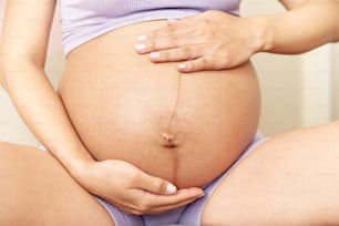 uma mulher grávida segurando sua barriga em suas mãos