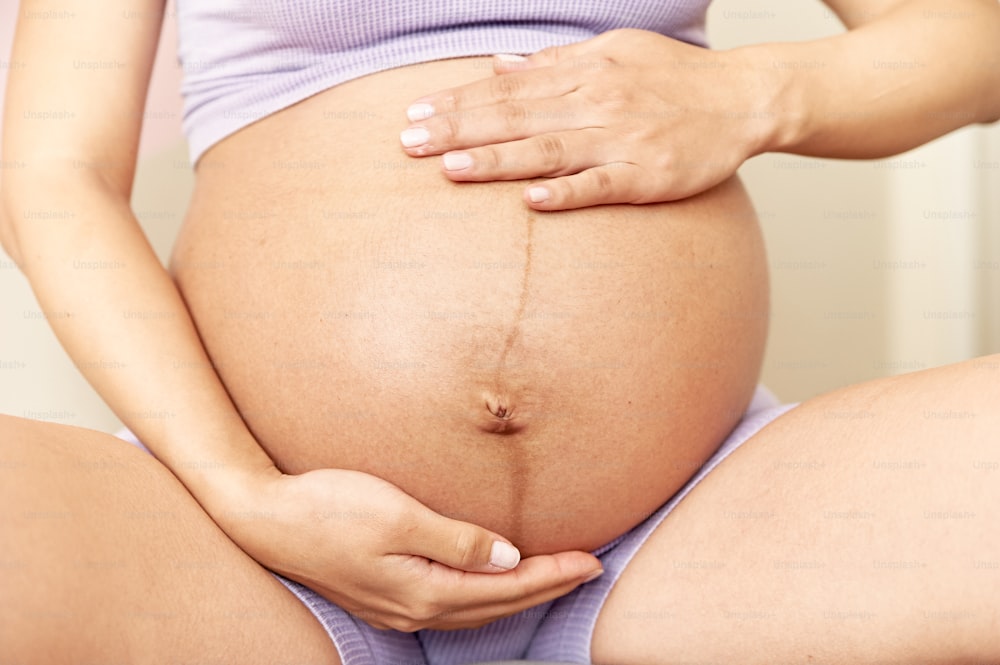 une femme enceinte tenant son ventre dans ses mains