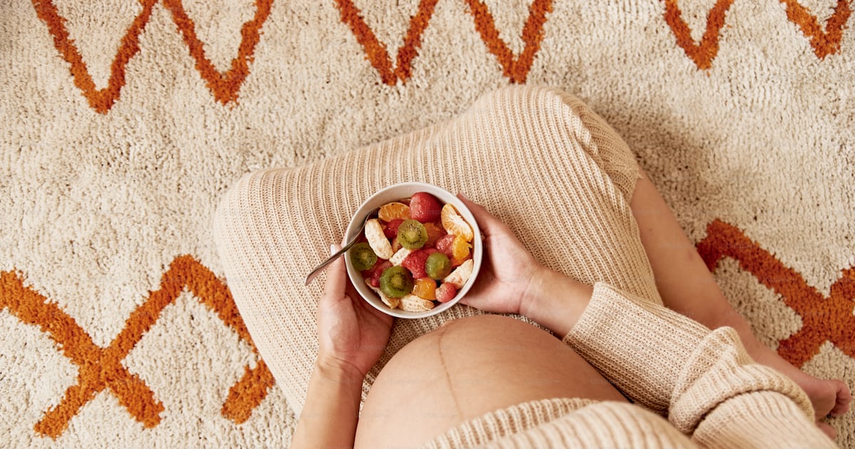 A woman laying on a rug holding a bowl of fruit photo – Healthy eating ...