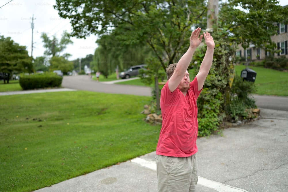 a man in a red shirt reaching up to catch a frisbee