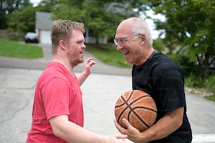 a man holding a basketball next to another man