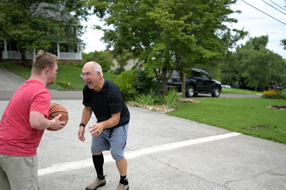 Un uomo che tiene un pallone da basket mentre è in piedi accanto a un altro uomo