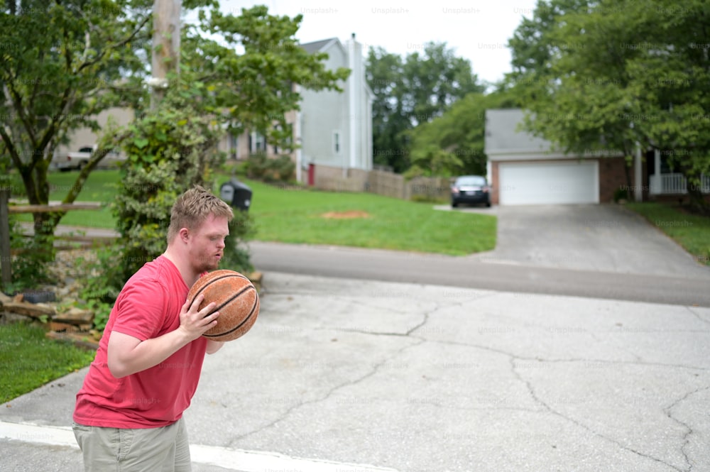 Un hombre con una camisa roja sosteniendo una pelota de baloncesto