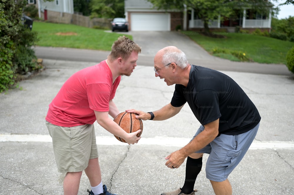 Un hombre sosteniendo una pelota de baloncesto mientras está de pie junto a otro hombre
