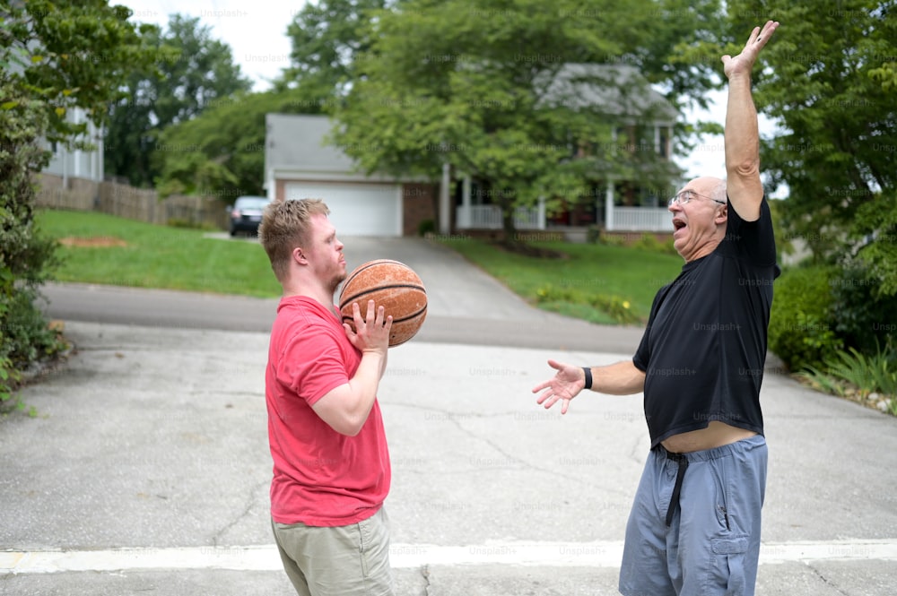 two men are playing basketball in a driveway