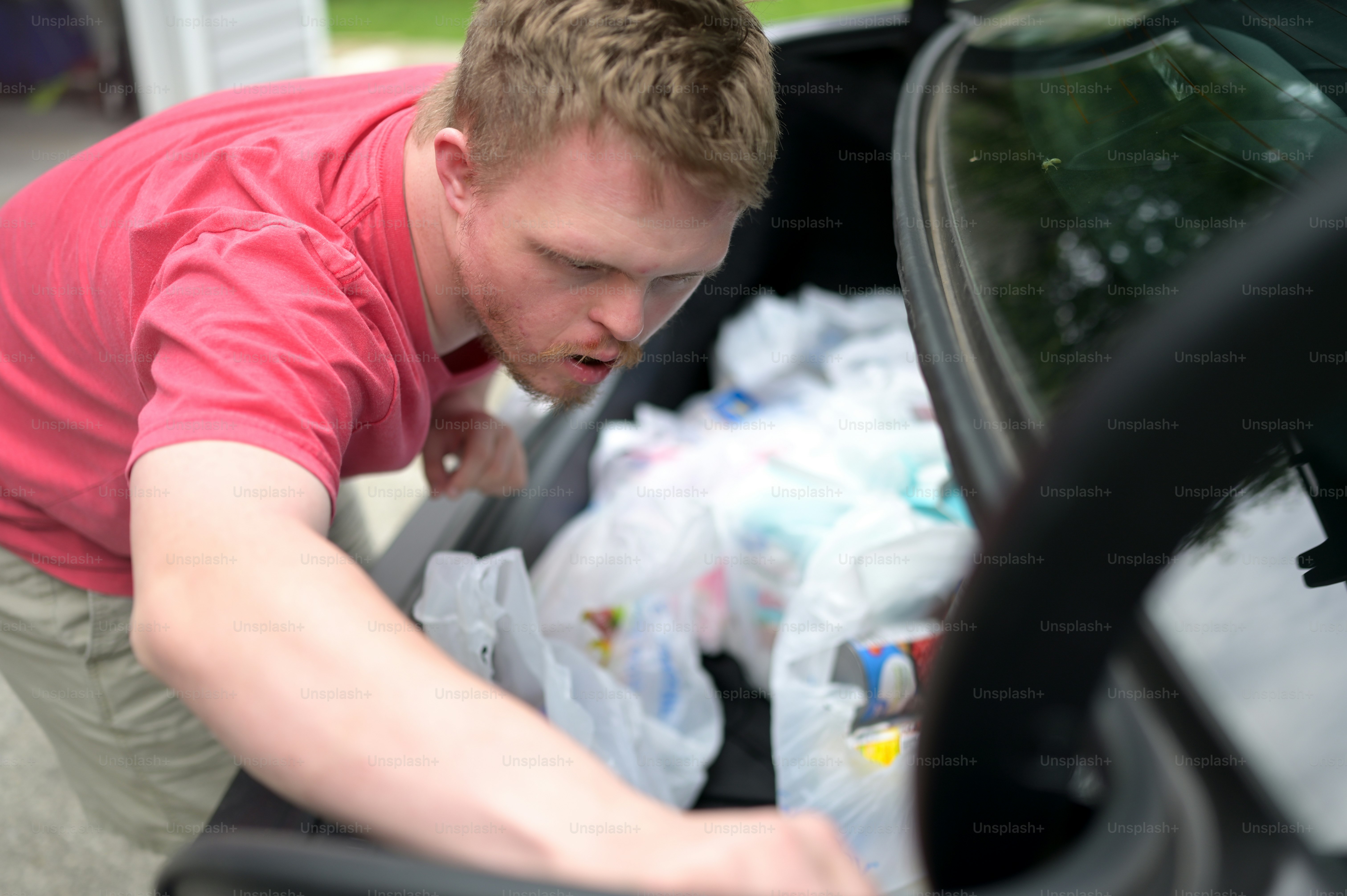 a man looking into the trunk of a car