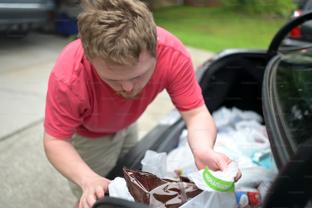 a man putting food in the back of a car