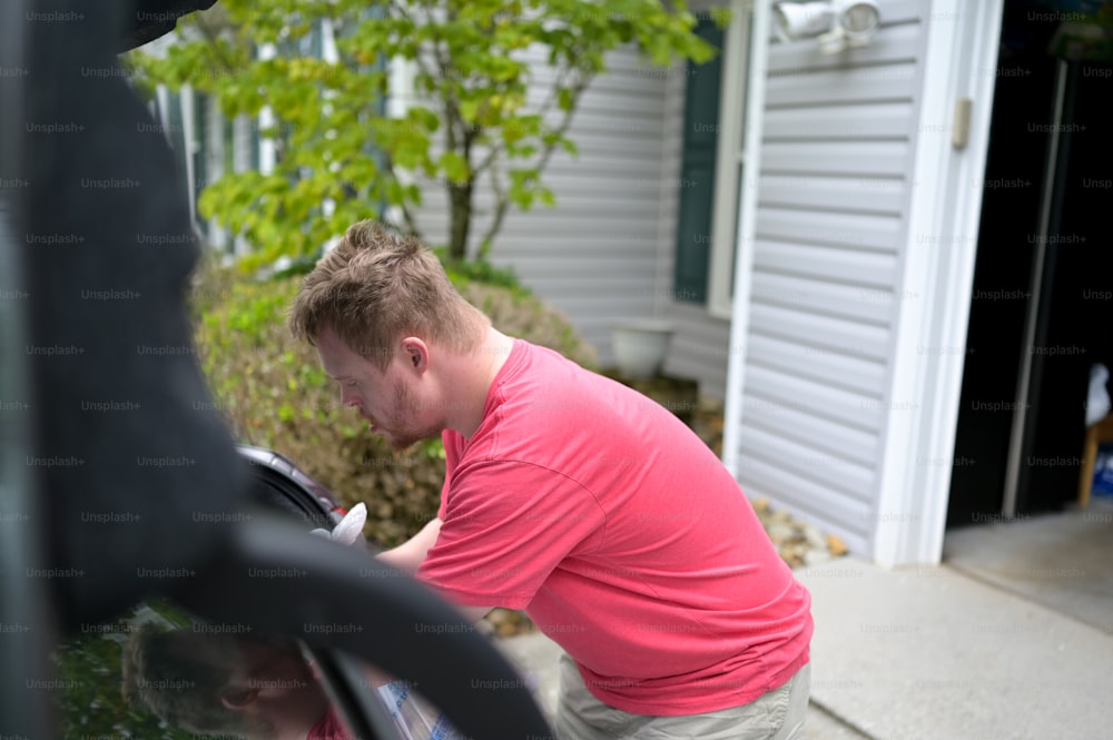 a man in a pink shirt looking into a car window