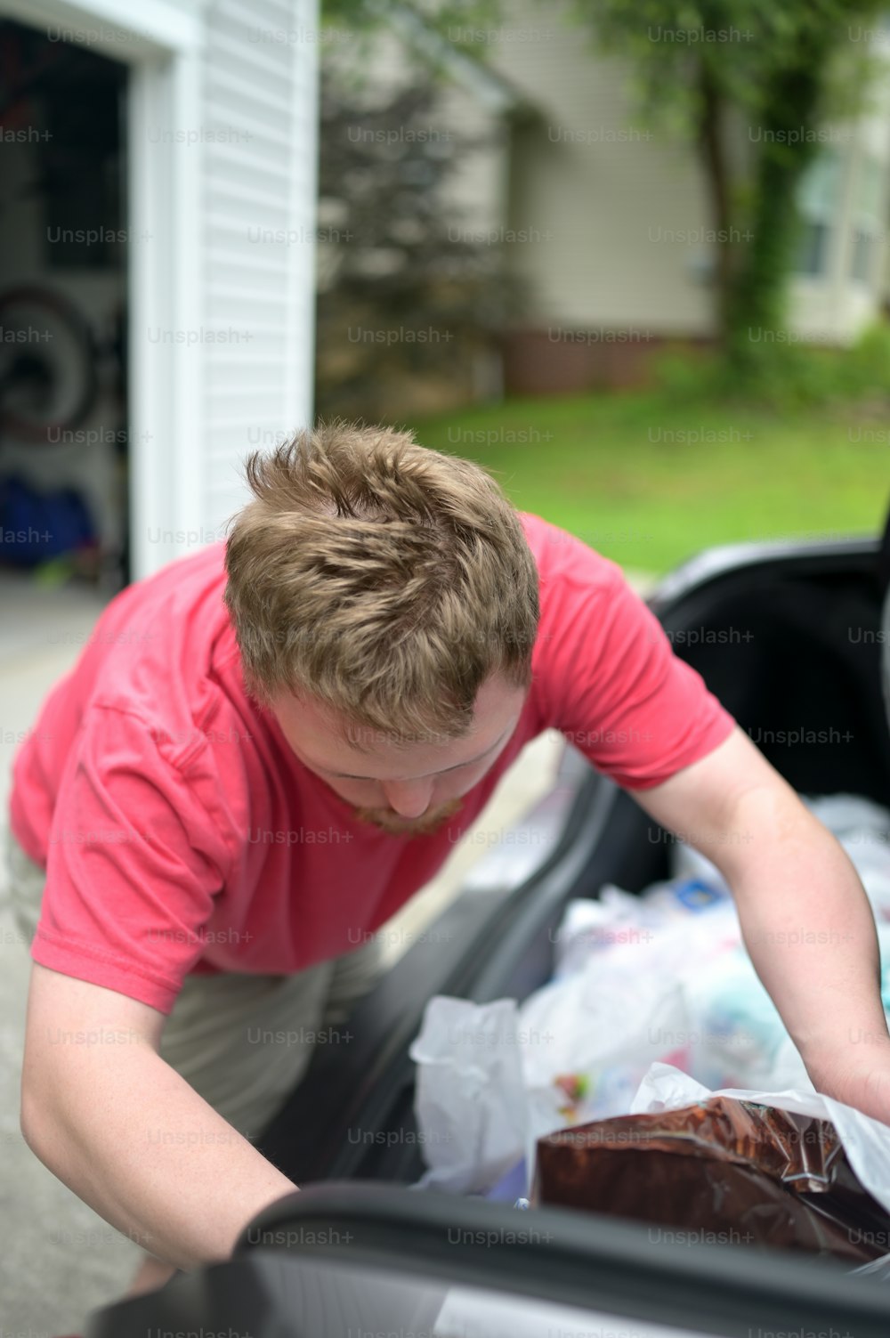 a man putting a bag of food into a car trunk