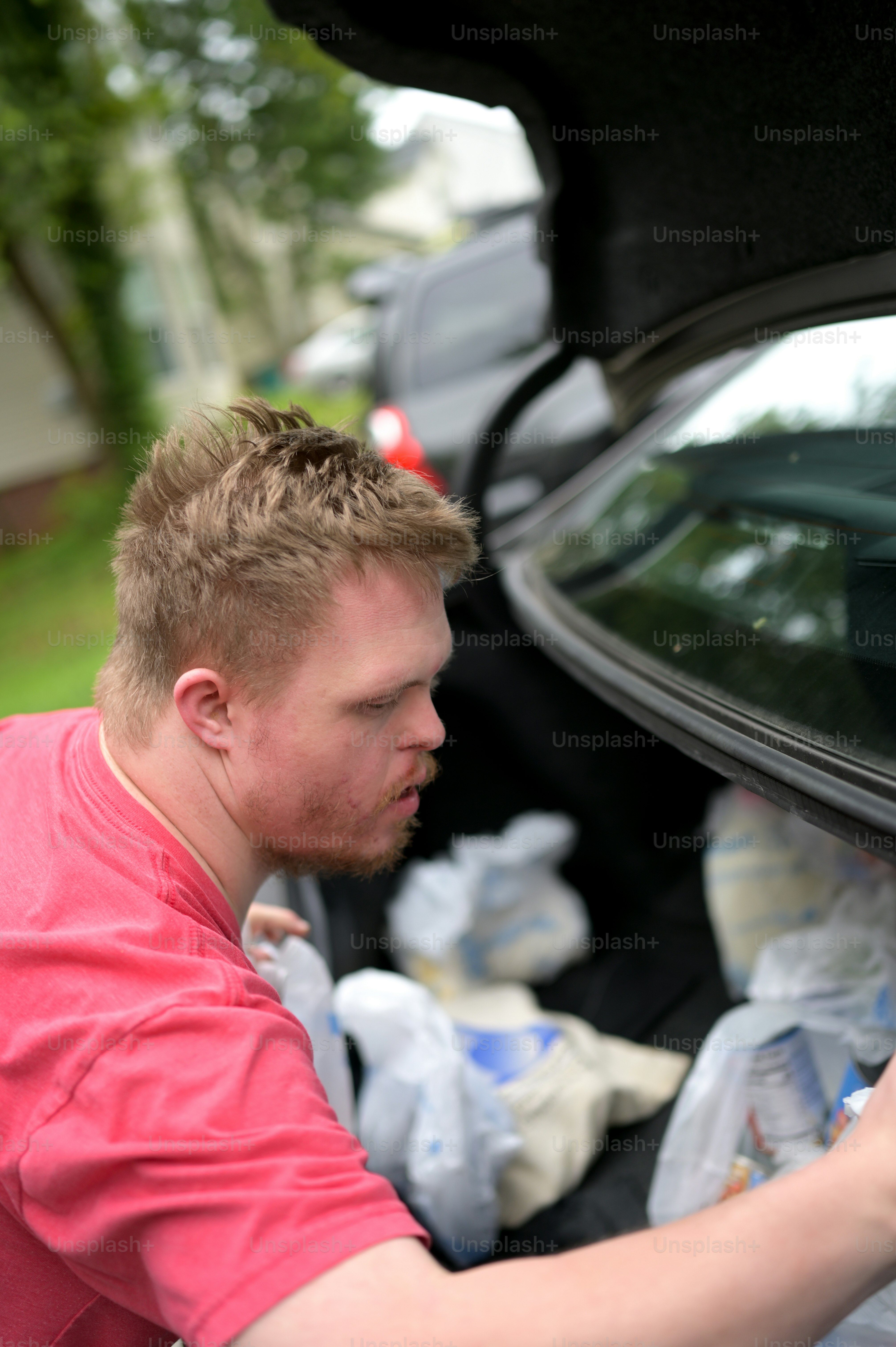 a man in a red shirt looking into a car