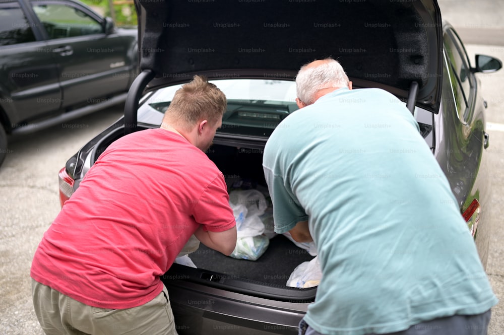 two men loading items into the trunk of a car