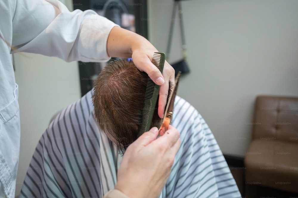 a person cutting another persons hair with a comb