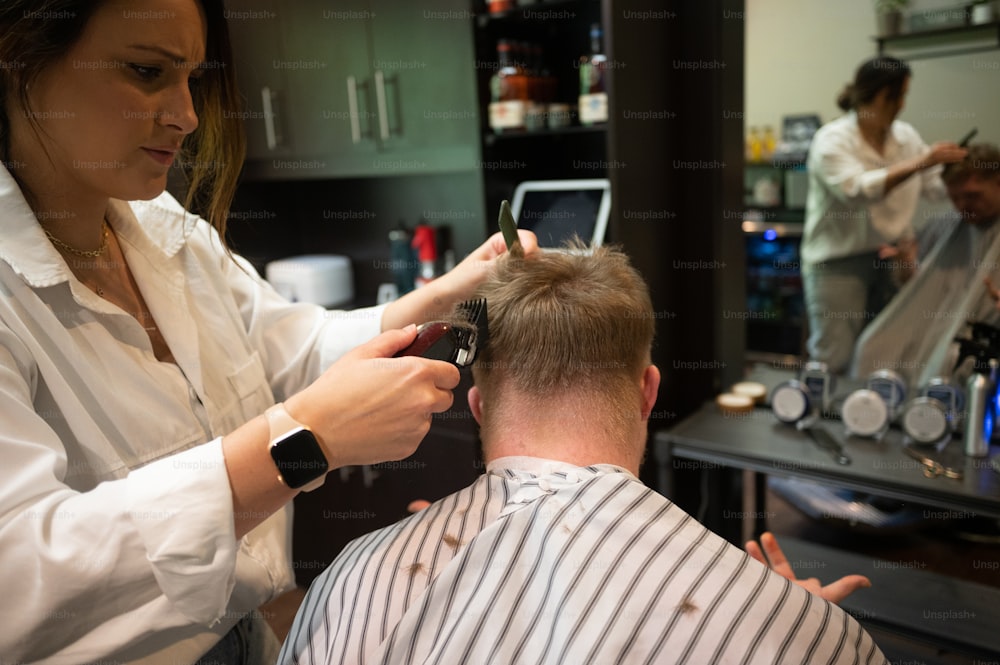 Une femme coupe les cheveux d’un homme dans un salon de coiffure