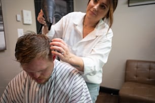 a woman cutting a man's hair with a hair dryer