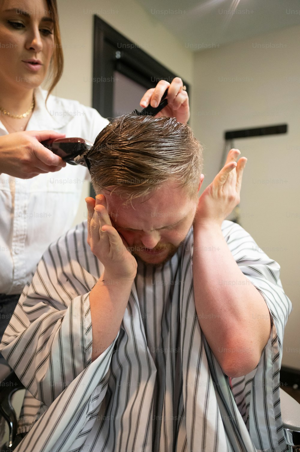a man getting his hair cut by a woman