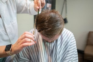 a woman cutting a mans hair with a pair of scissors
