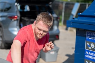 Un uomo in piedi accanto a un bidone della spazzatura blu