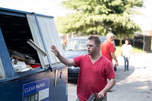 a man standing next to a blue trash truck