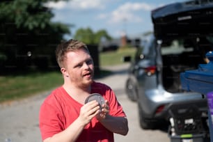 Ein Mann mit einem Frisbee, der neben einem Auto steht
