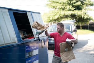 青と白のトラックの横に茶色の紙袋を持つ男