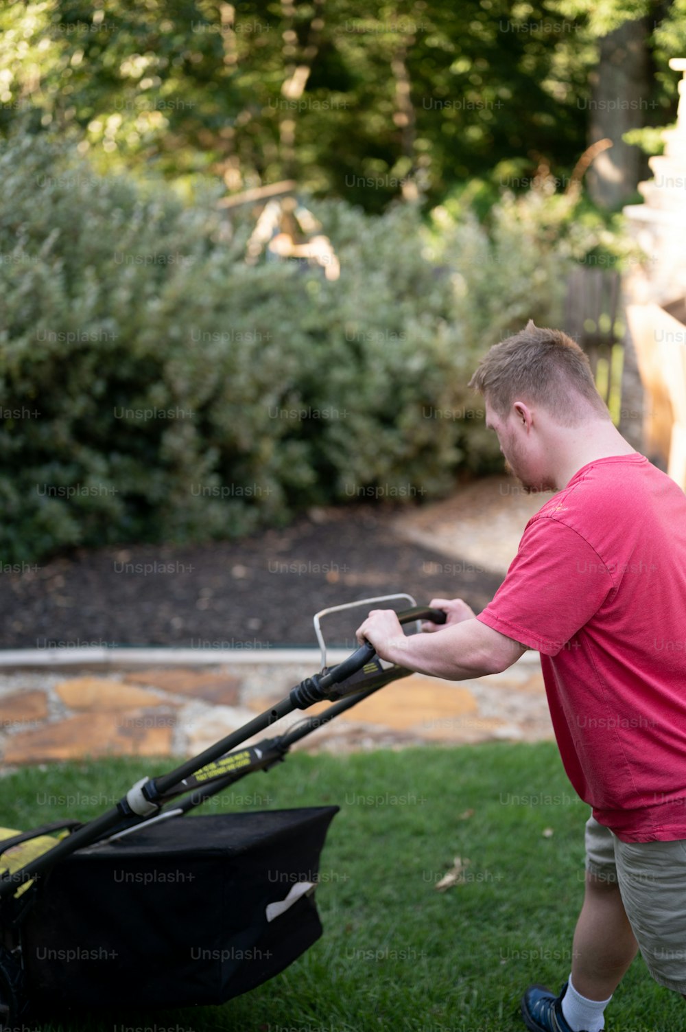 a man pushing a lawn mower in a yard