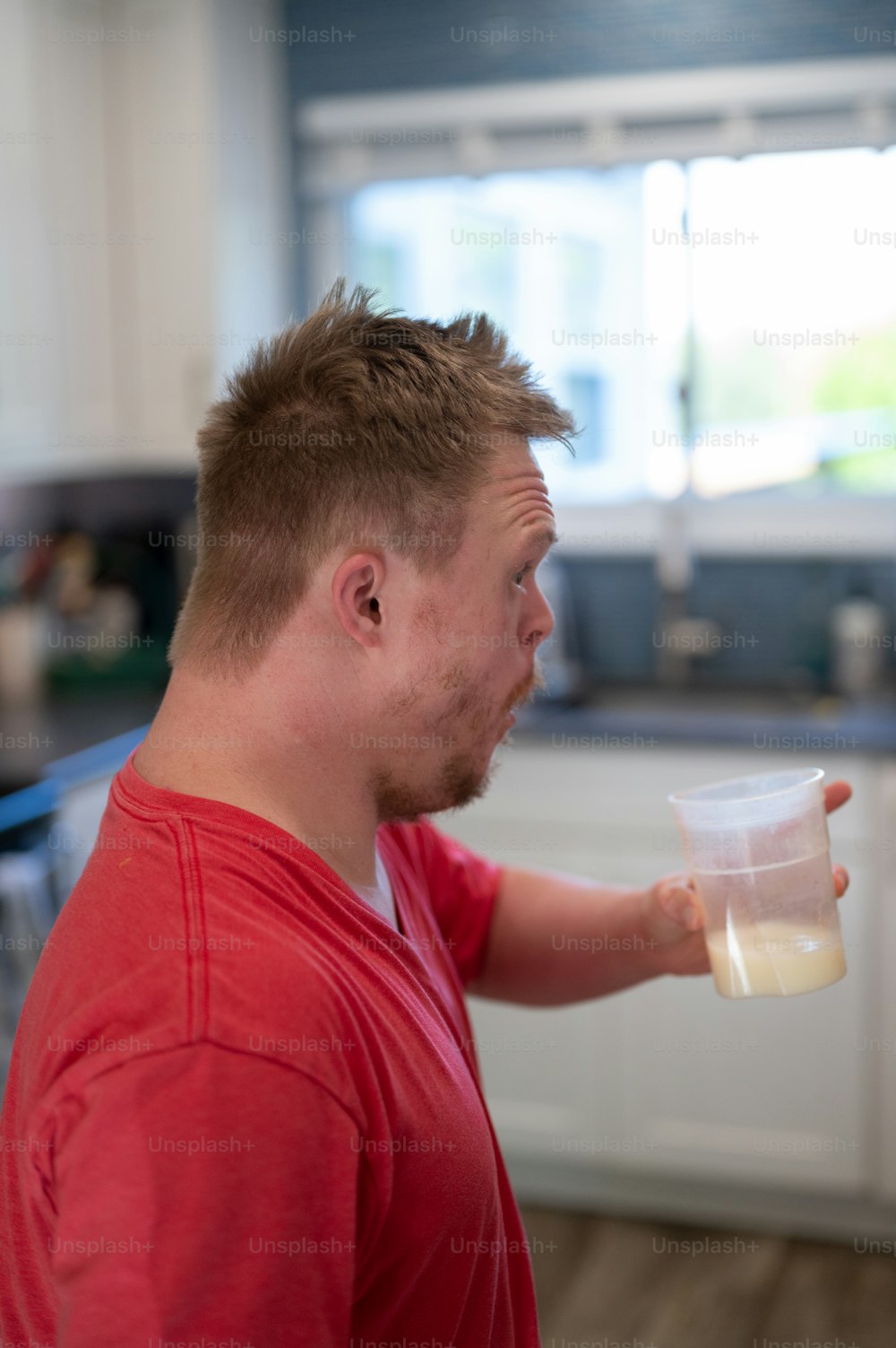 Ein Mann in einem roten Hemd, der eine Tasse Milch hält