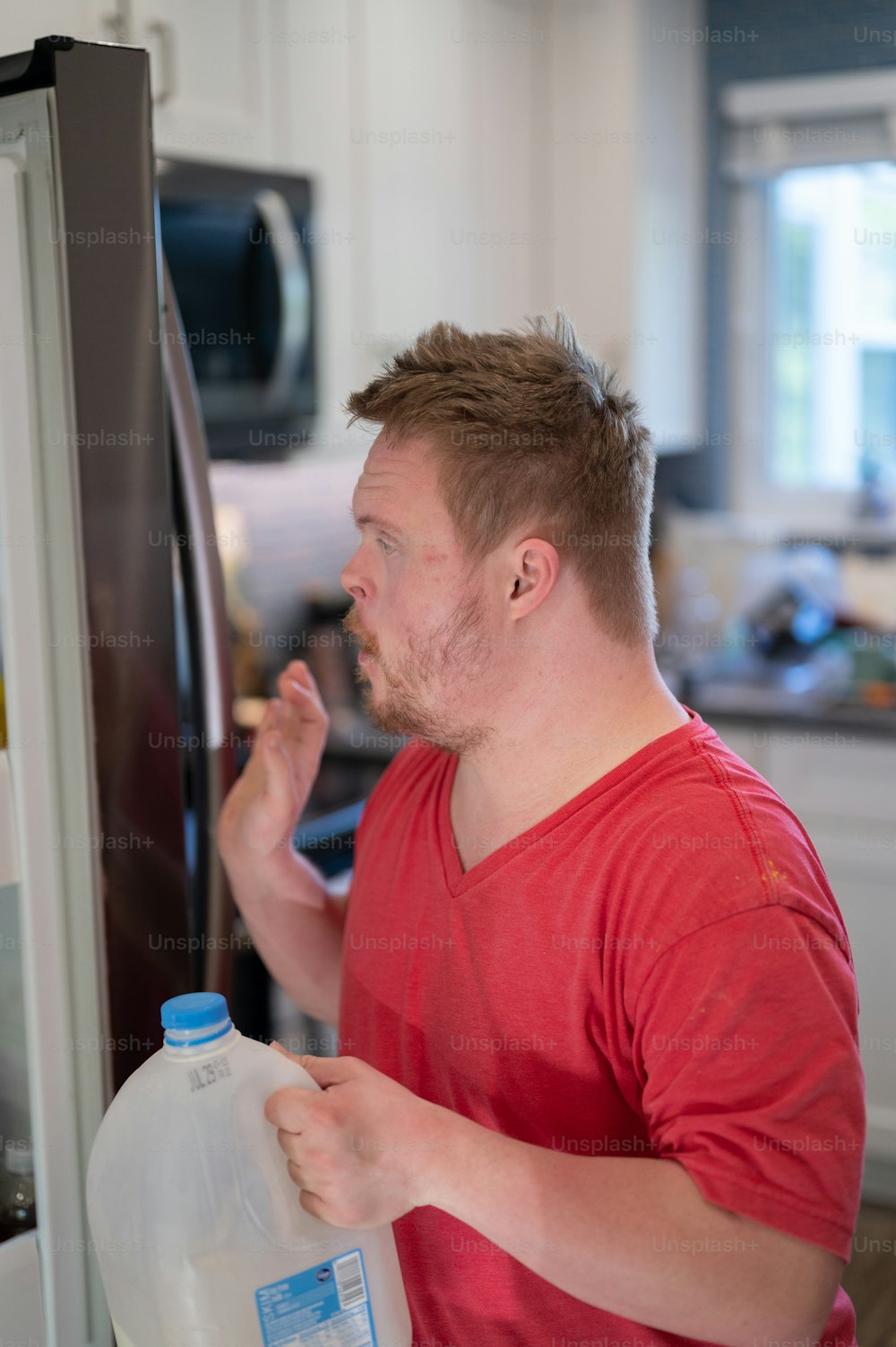 Ein Mann, der vor einem Kühlschrank steht und einen Krug Milch in der Hand hält