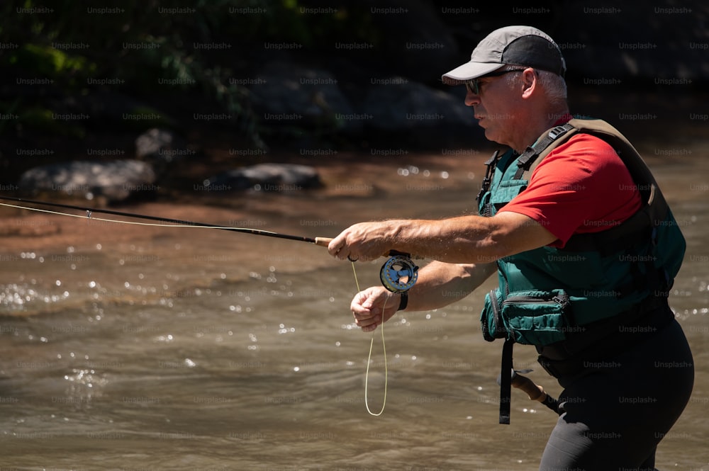 a man holding a fishing rod while standing in a river
