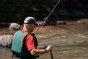 a man in a red shirt is holding a fishing rod
