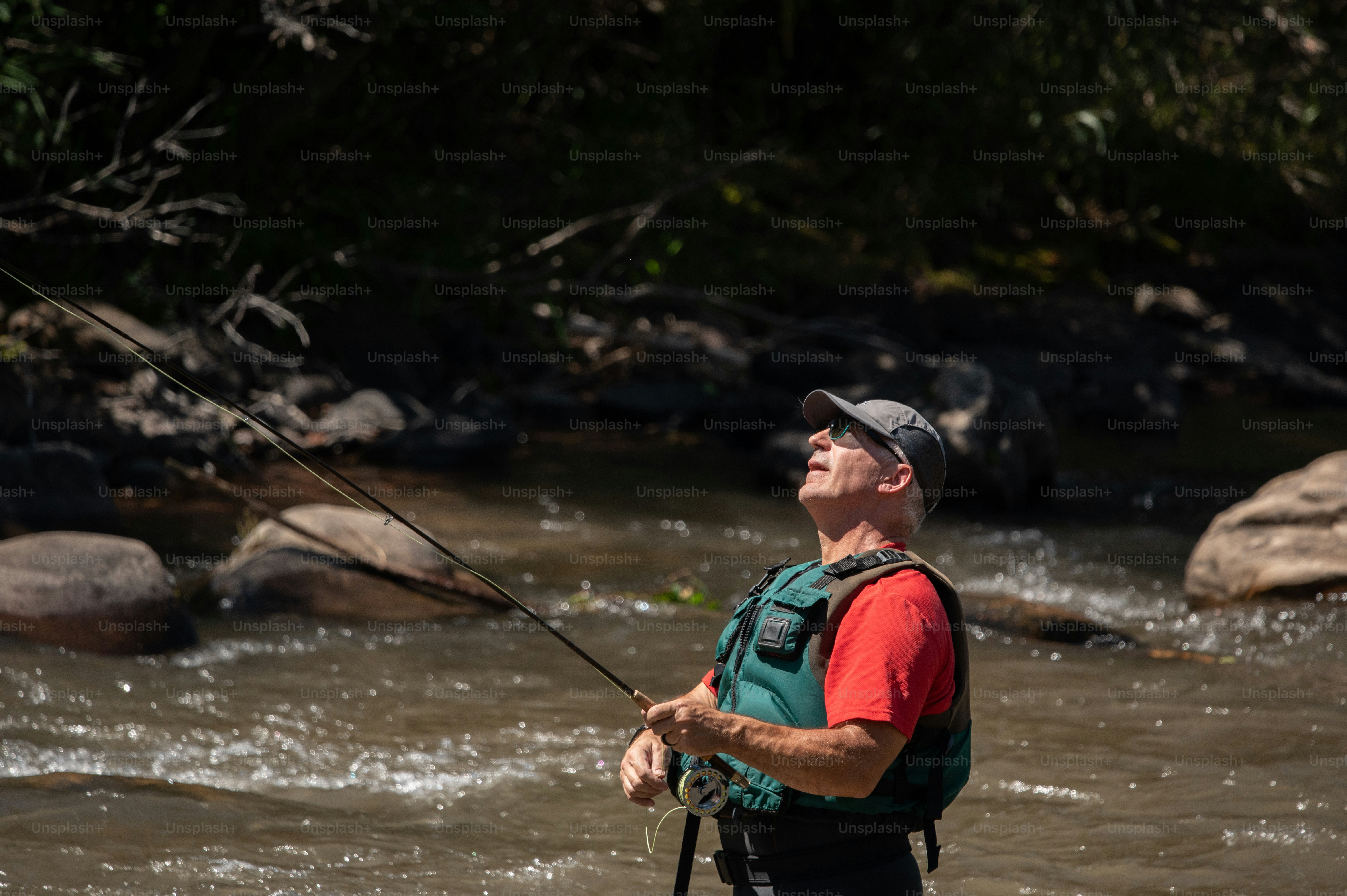 a man standing in a river while holding a fishing rod