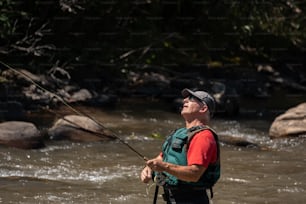 um homem parado em um rio enquanto segura uma vara de pesca