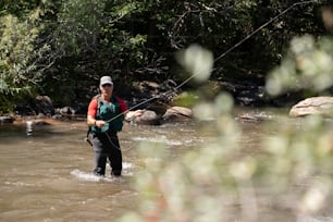 a man standing in a river while holding a fishing rod