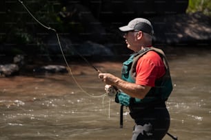 a man standing in a river while holding a fishing rod