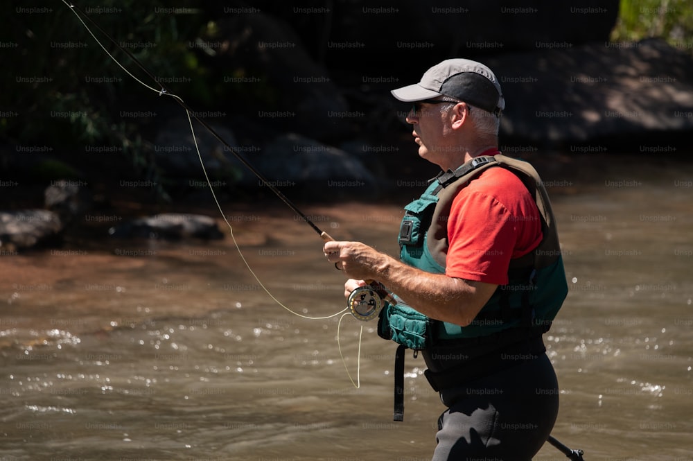 um homem parado em um rio enquanto segura uma vara de pesca