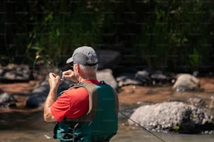 um homem pescando em um rio com uma vara de pesca