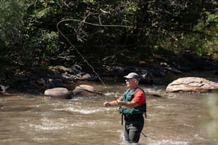 a man standing in a river while holding a fishing rod