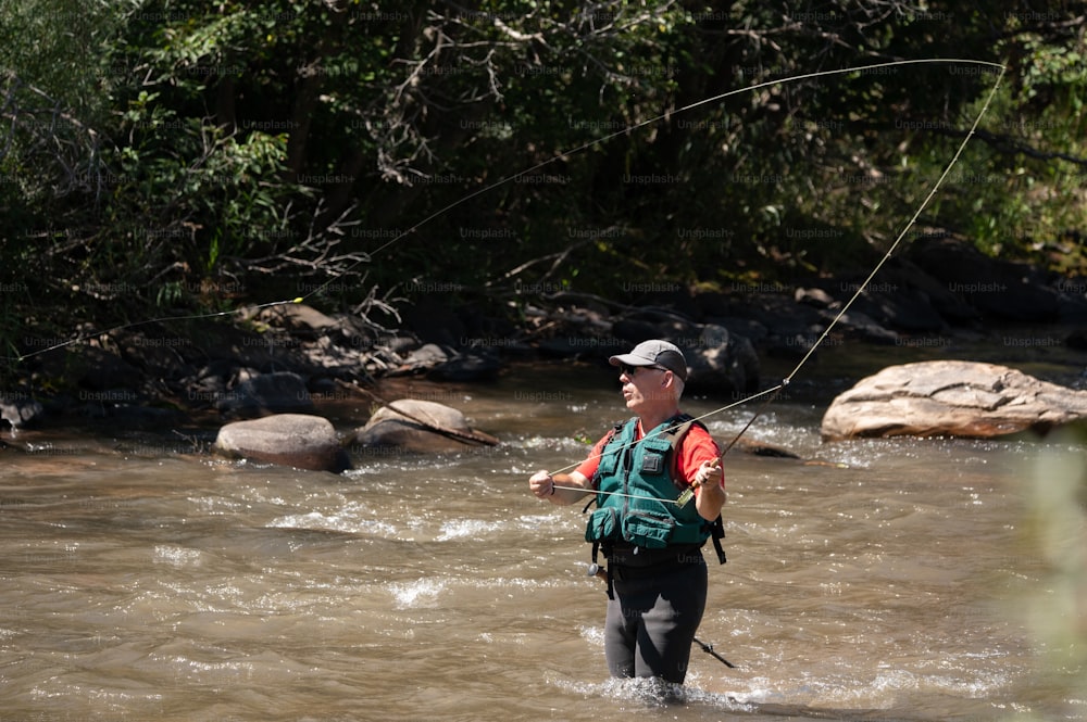 un homme debout dans une rivière tout en tenant une canne à pêche